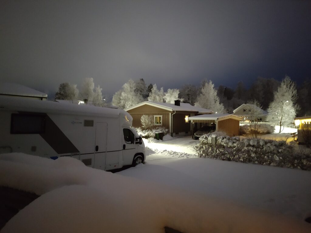 Husbil täckt av snö på parkeringen – en vinterbild som fångar känslan av husbilsdrömmar i vintertid.