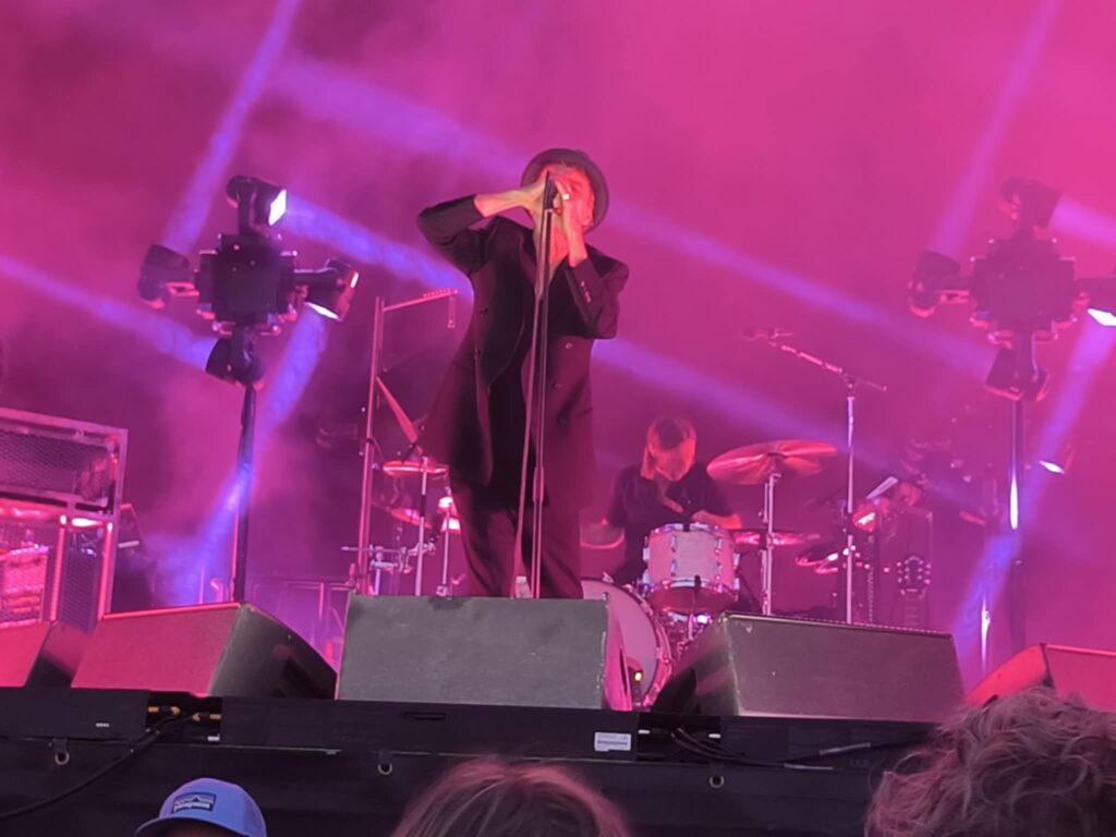 Thåström concert Karlstad – Thåström leaning forward at the microphone with drummer behind.