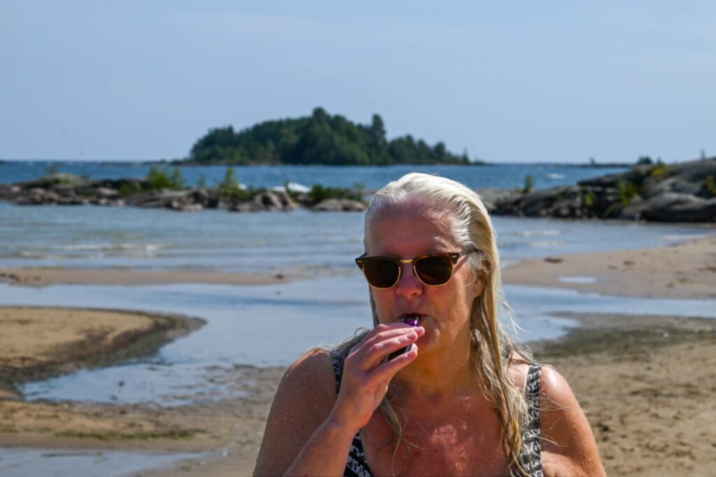 Woman with sunglasses at the beach, a day by the water in summer sunlight Carina Ikonen Nilsson