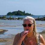 Woman with sunglasses at the beach, a day by the water in summer sunlight Carina Ikonen Nilsson