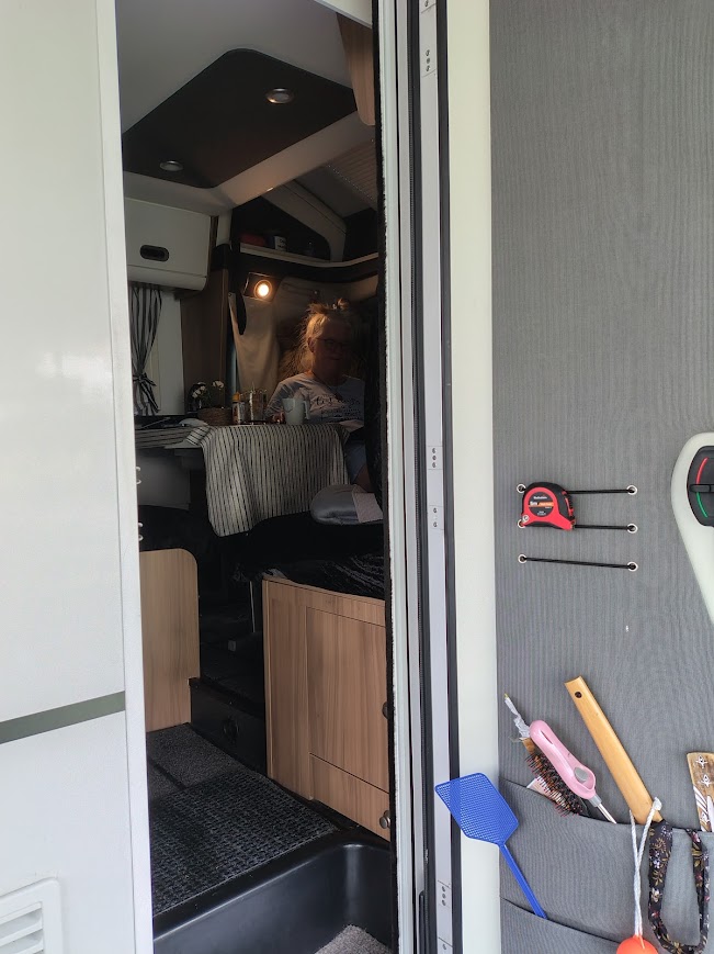 Utsikt in i husbilen med någon som sitter och läser vid bordet på Hanatorp Camping