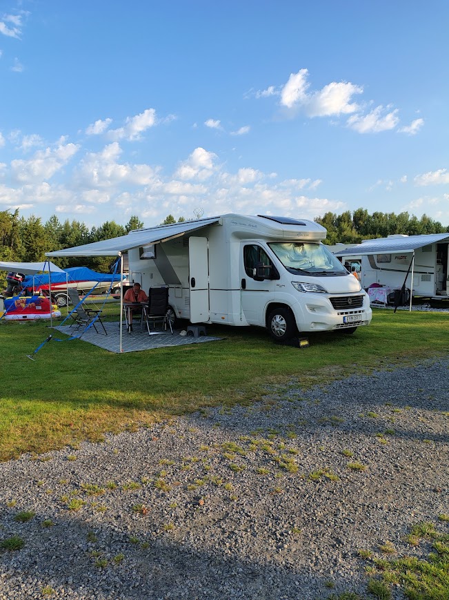 Husbilen parkerad på Hanatorp Camping med markis och stolar utanför en solig eftermiddag