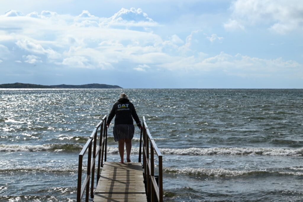 En mormor /farmor går ut på en brygga mot havet – en symbol för balans och vägar som går att bygga mellan närhet och avstånd