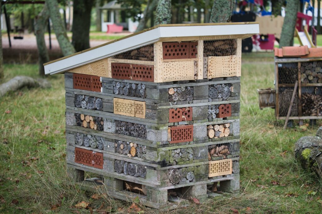 Insektshotell i Skräcklanparken byggt av trä, tegel och borrade stockar – en påminnelse om hur vi skapar skydd för insekter men ofta stänger dörren för människor på flykt.