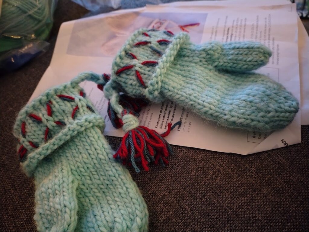 Handstickade ljusblå vantar med röda detaljer, gjorda till barnbarnet Alfred.